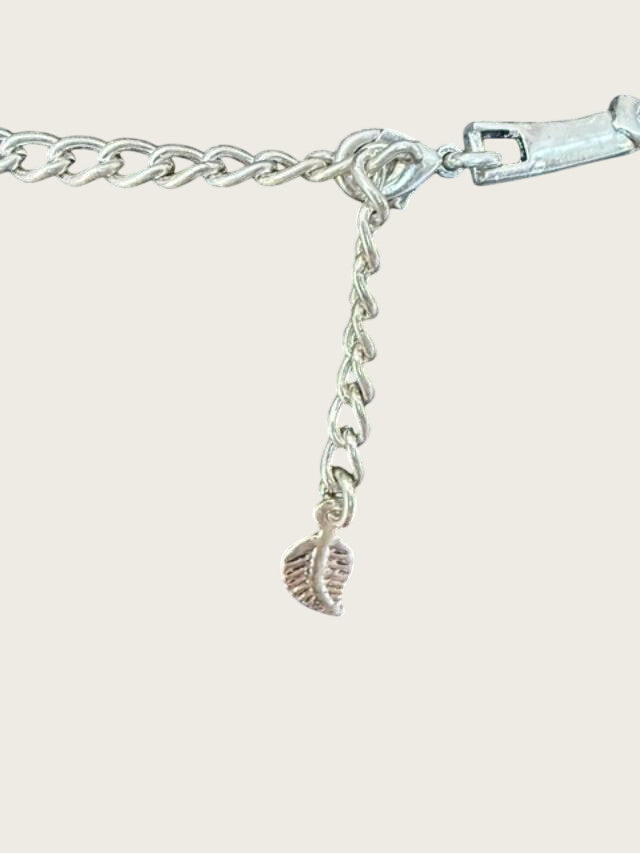 Belcaro Heirlooms silver-tone necklace extender chain with a small leaf-shaped charm on a black display stand