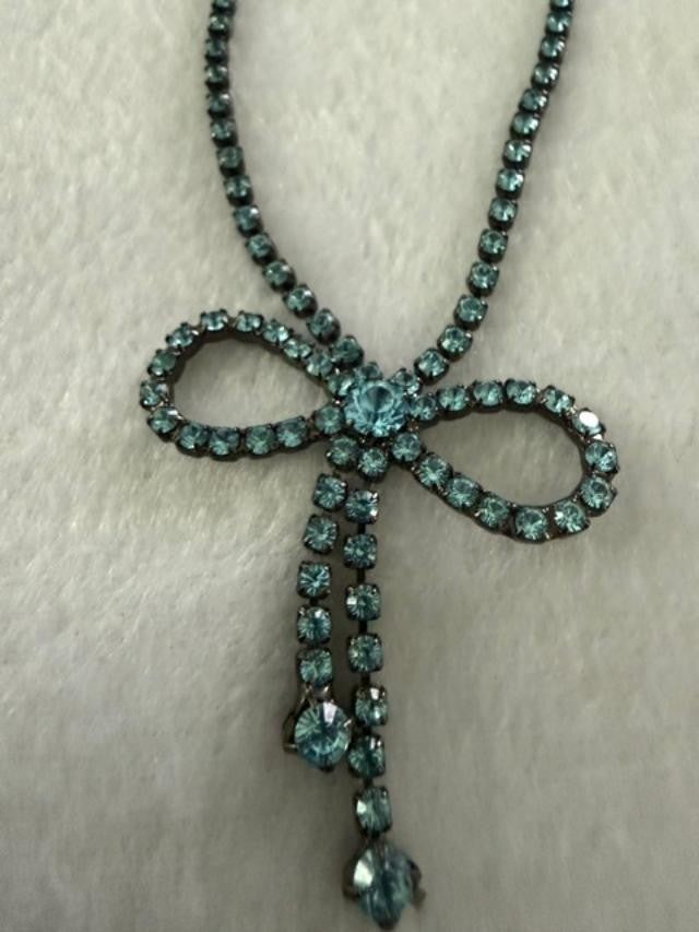 Vintage blue rhinestone bow necklace set in dark antiqued metal.