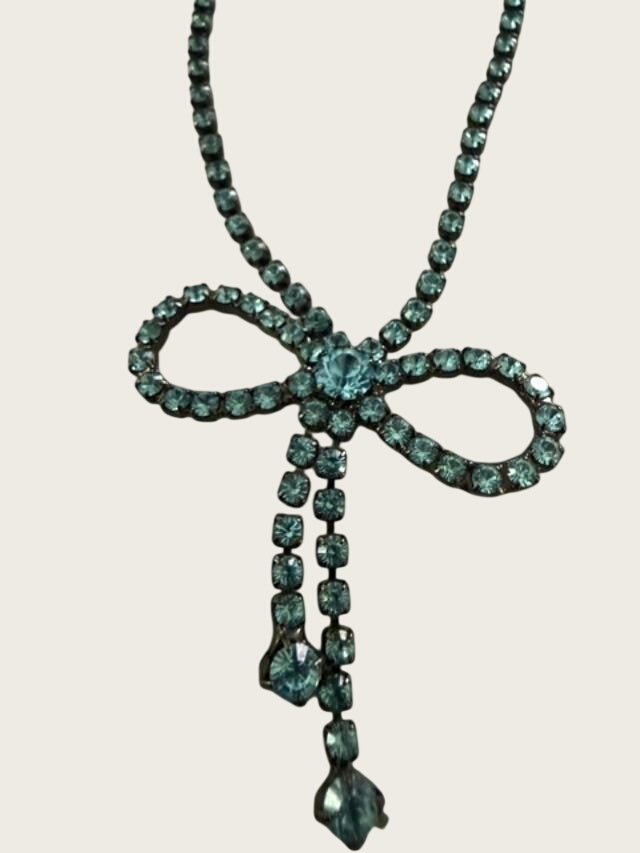 Vintage blue rhinestone bow necklace set in dark antiqued metal.