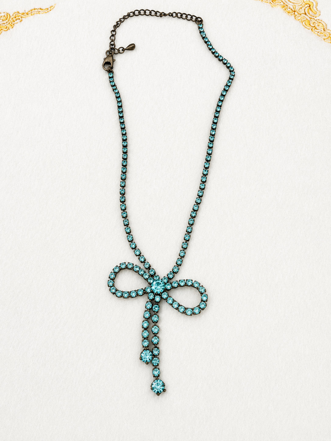 Vintage blue rhinestone bow necklace set in dark antiqued metal.