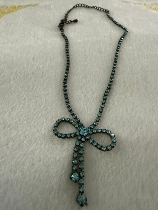 Vintage blue rhinestone bow necklace set in dark antiqued metal.